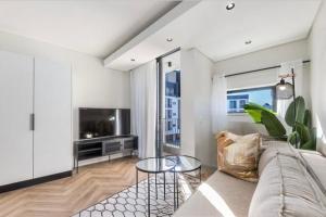 a living room with a couch and a tv at On Park - Century City Lux Studio Apartment in Cape Town