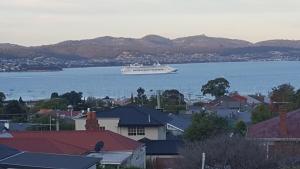a cruise ship in the water near a city at In the Hart of Hobart in Sandy Bay