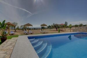 a swimming pool in front of a beach with umbrellas at Villa Damara in Albox