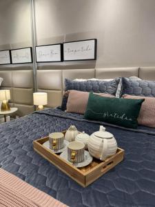 a bed with a tray with plates and dishes on it at Estúdio Lumière Moema in Sao Paulo +66 photos