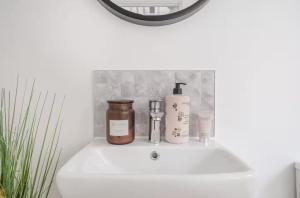 a bathroom sink with two bottles and a mirror at Spacious 4 Bed Home for Contractors & Families in Blunham +31 photos