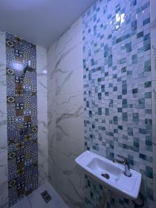 La salle de bains est pourvue d'un lavabo et de mosaïques sur le mur. dans l'établissement Ami D'or Hostel, à Taghazout 57 autres photos