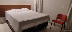 a bed with a red chair in a room at Pousada horbis in Guarabira