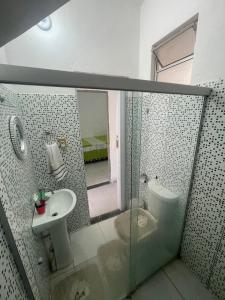a bathroom with a glass shower and a sink at Quarto privativo La Paz in Aracaju