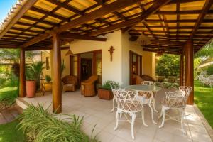 a patio with a table and chairs under a wooden pergola at Casa de Praia em Guarajuba-Genipabu-BA in Guarajuba