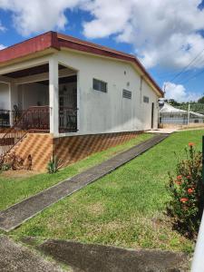 een wit huis met een veranda en een tuin bij Chambre lumineuse chez L'habitant in Le Lamentin