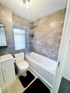 a bathroom with a tub and a toilet and a sink at Modern 2-Bed w Parking & Garden in Woolwich