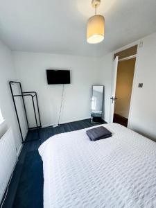 a bedroom with a white bed and a flat screen tv at Modern 2-Bed w Parking & Garden in Woolwich +4 photos