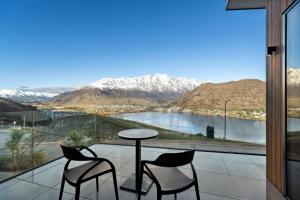 a balcony with two chairs and a table and a view at Elevated Tranquility Luxe Lakeview Horizons in Queenstown