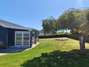 a house with a yard with a tree in front of it at 6 person holiday home in Augustenborg in Augustenborg