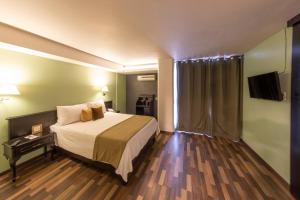 a hotel room with a bed and a flat screen tv at Lusitania Suites in Orizaba