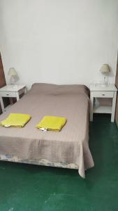 a bedroom with a bed with yellow sheets and two tables at Monoambiente Para 2 in Belén