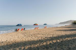 a beach with chairs and umbrellas and the ocean at Villa Alhelí, Oceanview Escape with Private Pool in Sayulita +21 photos