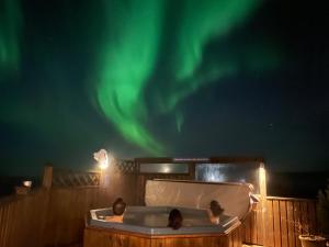 deux enfants assis dans une baignoire sous les aurores boréales dans l'établissement Lambastadir Guesthouse, à Selfoss