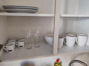 a kitchen shelf with white cups and vases on it at Tini in Hayange