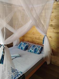 a bed with blue pillows under a mosquito net at Manglar Eco Resort in La Barra