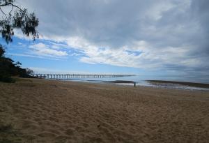 a sandy beach with a pier in the water at Spacious - Sunrise over the sea in Urangan