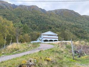 a building on a dirt road in front of a mountain at Great House with a panoramic view in Storsæter