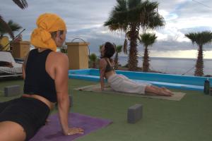a couple of women doing yoga by a pool at The Tree House Camp in Adeje +21 photos