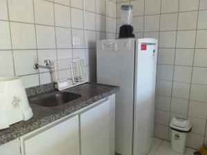 a kitchen with a sink and a white refrigerator at Flat do Golfinho in Tamandaré