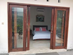 a bedroom with a bed and sliding glass doors at Gusti Homestay in Munduk