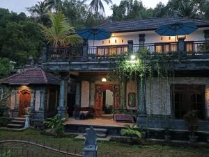 a house with a balcony on top of it at Gusti Homestay in Munduk