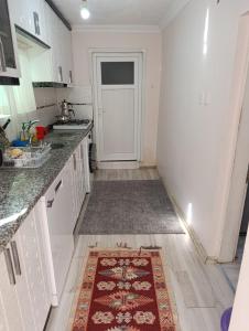 a kitchen with white cabinets and a rug on the floor at Koru Pansiyon in Gelibolu