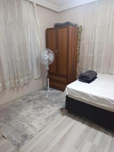 a bedroom with a bed and a dresser and a fan at Koru Pansiyon in Gelibolu