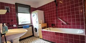a red tiled bathroom with a tub and a washing machine at Ganzes Ferienhaus in Kassel mit umzäunten 1000qm Garten, Komfort Küche, Bad, Wohnzimmer, 4 Schlafzimmer, 8 Betten, Gratis Parkplätze, BBQ Pavillion, so privat wie zu Hause in Kassel