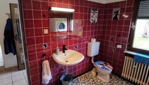 a red tiled bathroom with a sink and a toilet at Ganzes Ferienhaus in Kassel mit umzäunten 1000qm Garten, Komfort Küche, Bad, Wohnzimmer, 4 Schlafzimmer, 8 Betten, Gratis Parkplätze, BBQ Pavillion, so privat wie zu Hause in Kassel +37 photos