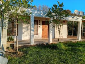 a white house with a wooden door in a yard at Casa en Lago Merin Uruguay in Lago Merin