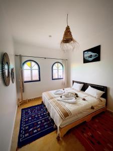 a bedroom with a large bed and two windows at Ifni Sunset in Sidi Ifni