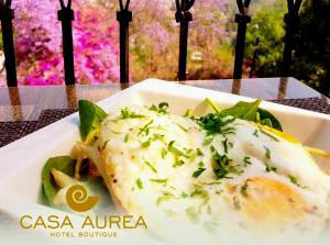 a plate of food with a fish with cheese and greens at Casa Aurea Hotel Boutique in Morelia