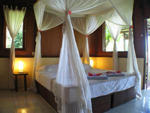 a bedroom with a canopy bed with white drapes at Bunaken Cha Cha Nature Resort in Bunaken