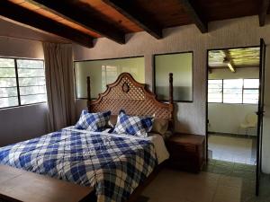 Schlafzimmer mit einem Bett mit einer karierten Decke und Fenstern in der Unterkunft Casa Grande, Casita, Gran Jardín, Juegos para 19 personas en el Pueblo in Valle de Bravo