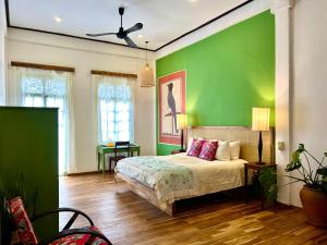 a green bedroom with a bed and a green wall at The Apsara in Luang Prabang