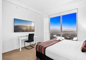 ゴールドコーストにあるLevel 45 Luxury Sub-Penthouse in Towers of Chevron - Hosted by Coastal Letting Co.のベッドと机と窓のある寝室