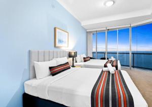 ゴールドコーストにあるLevel 45 Luxury Sub-Penthouse in Towers of Chevron - Hosted by Coastal Letting Co.のベッドが2つと大きな窓がある寝室