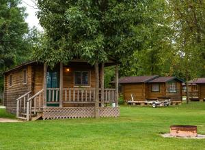 a log cabin with a porch and a tree at Fremont RV Campground Cottage 21 in Fremont