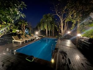 a swimming pool at night with chairs and trees at Ta Thai Cooking & Stay in Ban Khlong Tan
