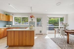 une cuisine avec des armoires en bois et une table et des chaises dans l'établissement Delightful Delta - 3 Bedroom House - Taroona, à Taroona 36 autres photos