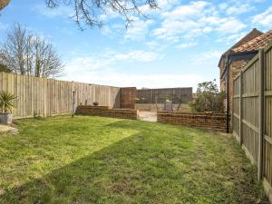 a backyard with a fence and a yard with grass at The Barn in Martham