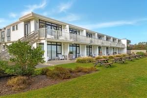 a large building with benches in front of it at Whispering Sands Beachfront Motel in Gisborne