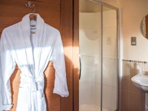 Una bata blanca colgada en la puerta de un baño. en Trelaw - Uk41532, en Ochiltree