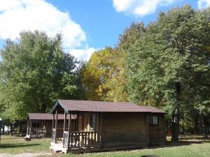 a small wooden cabin in a park with trees at Fremont RV Campground Cabin 8 in Fremont +2 photos