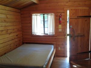 una piccola camera con un letto in una cabina con finestra di Fremont RV Campground Cabin 8 a Fremont