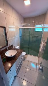 a bathroom with a glass shower and a sink at NAVEGA BEACH HOUSE - Casa 2 Andares - Rede Navega Hotéis in Navegantes