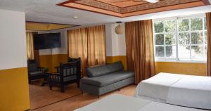 a bedroom with a bed and a couch and a chair at Hotel Benedicta in Mexico City