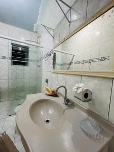 a white bathroom with a sink and a mirror at Chalé em ilhabela in Ilhabela