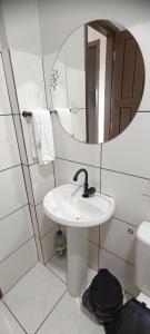 a white bathroom with a sink and a mirror at Exclusive space in the Center, affordable accommodation in Castanhal